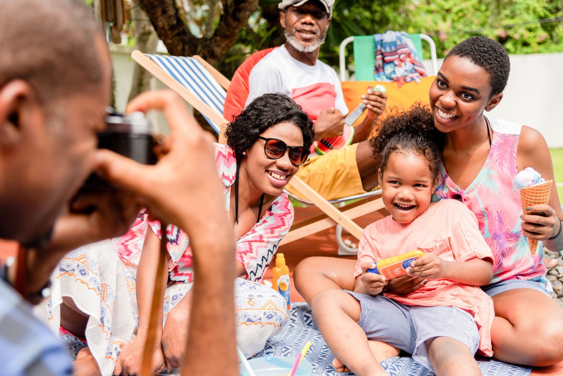 A grandfather, parents and a young child in a sunny backyard