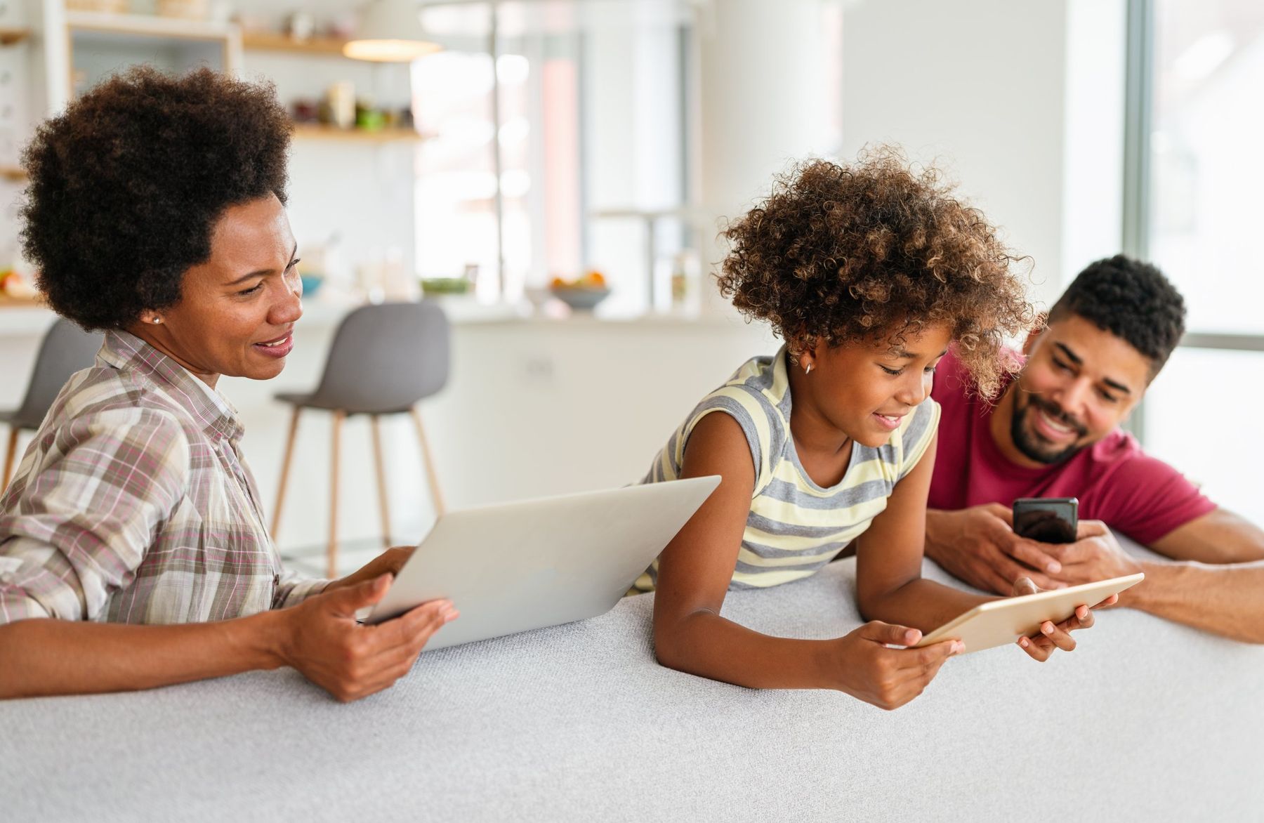 A family checking information together on a laptop, tablet and phone